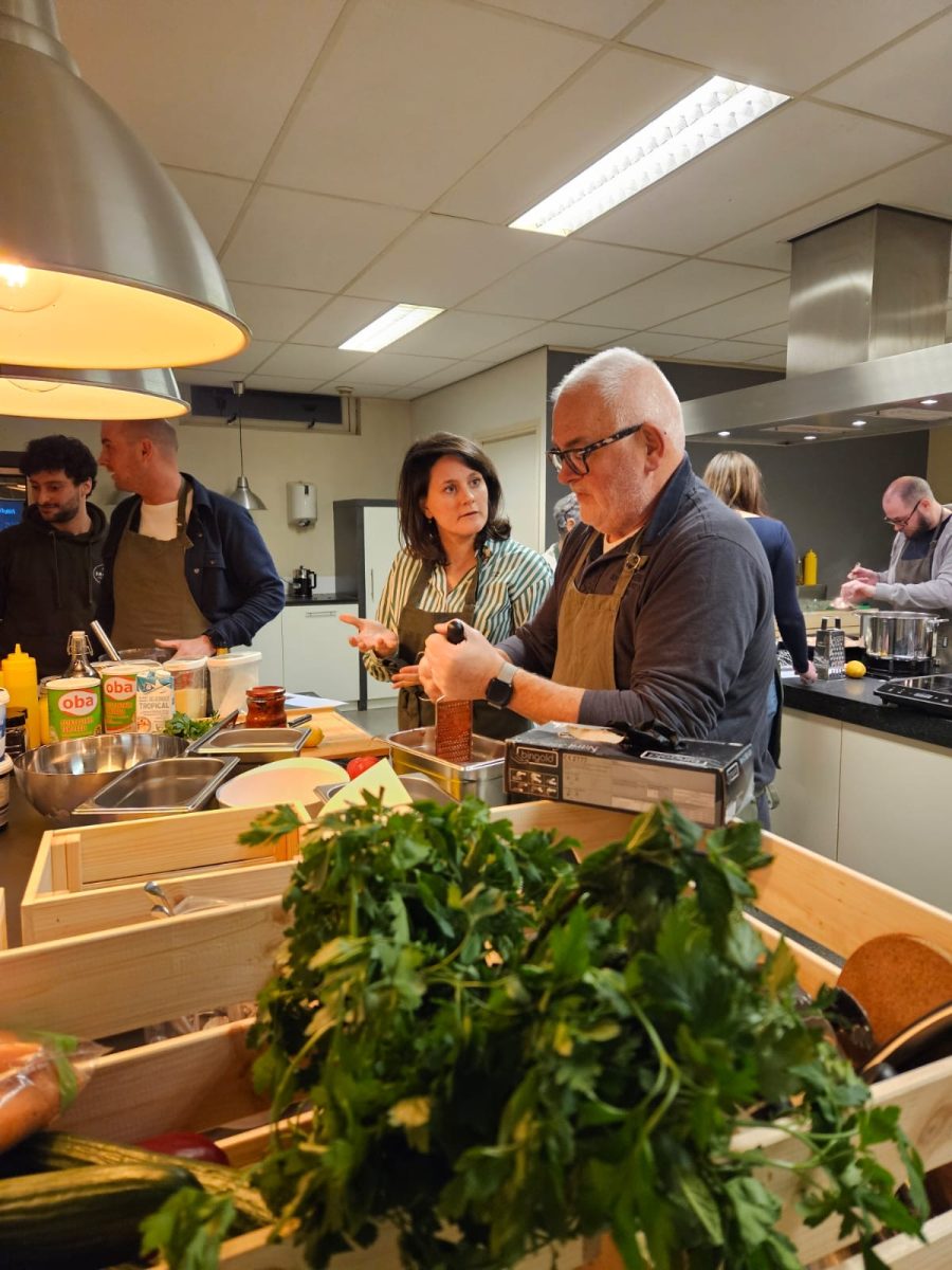 Samen koken: Collega's werken in duo's om groenten te snijden en gerechten te bereiden, met een ontspannen en vrolijke sfeer.