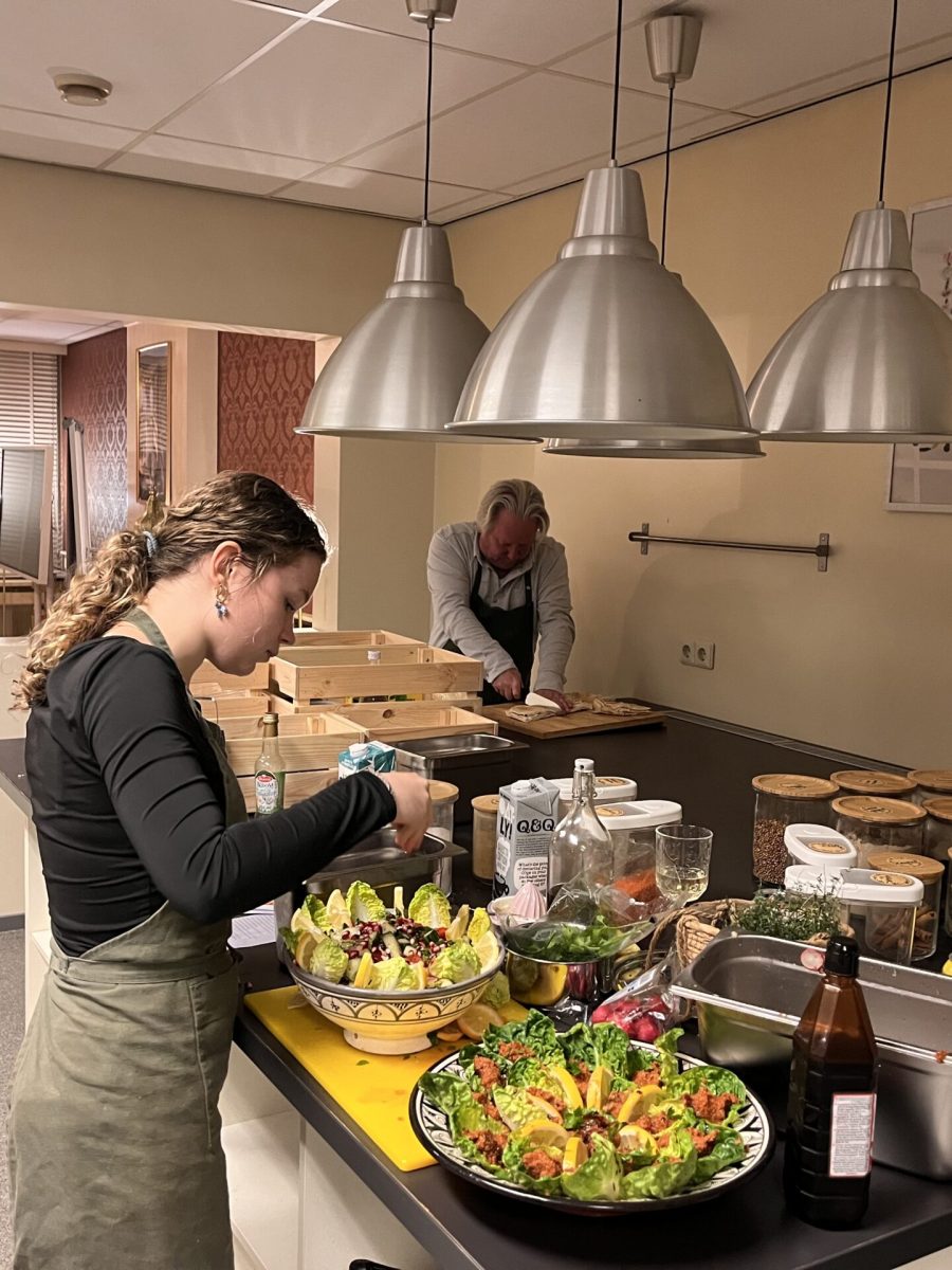 Arabische Ingrediënten verzamelen: Kinderen en ouders verzamelen verse ingrediënten van een tafel, lachend en pratend.